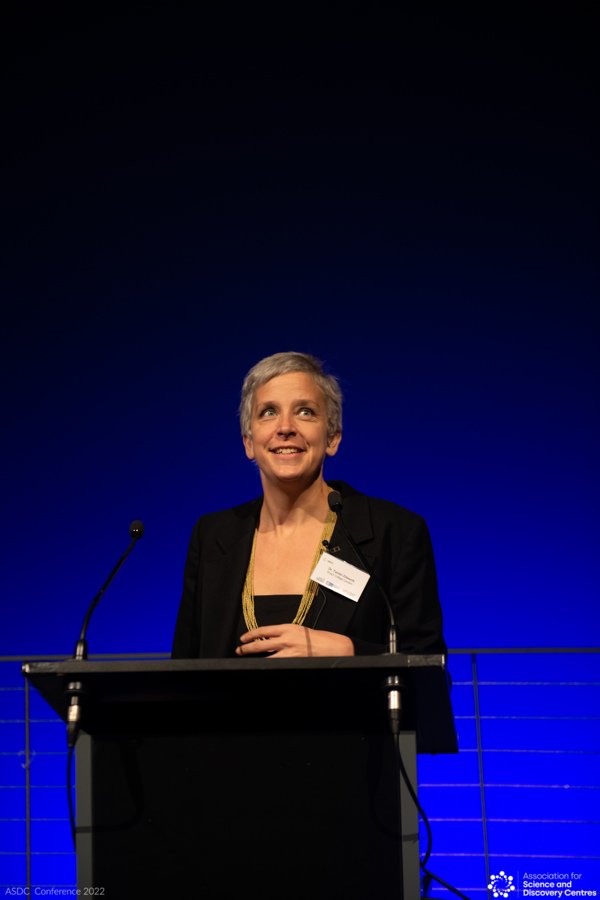 Photo of Dr Tamsin Edwards standing at a podium, smiling