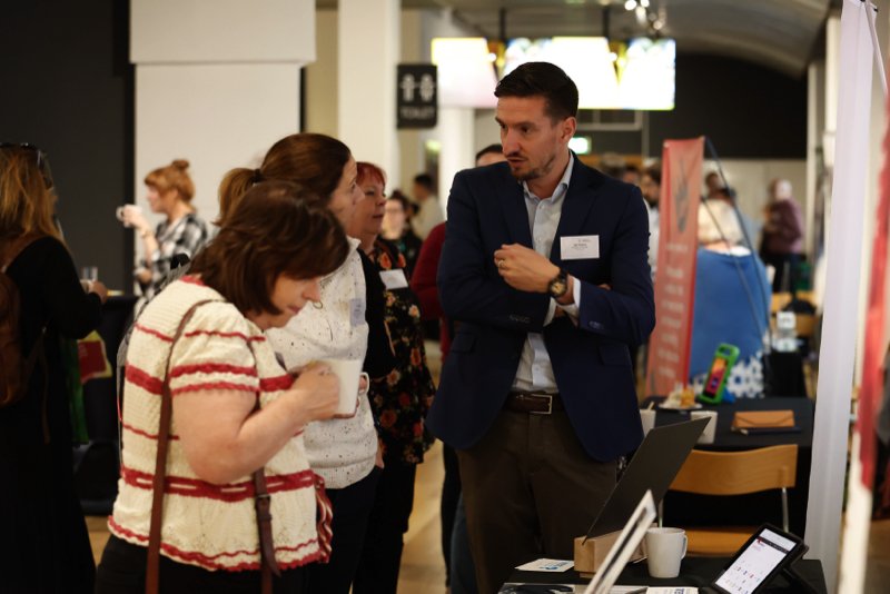 Male exhibitor talking to two female delegates