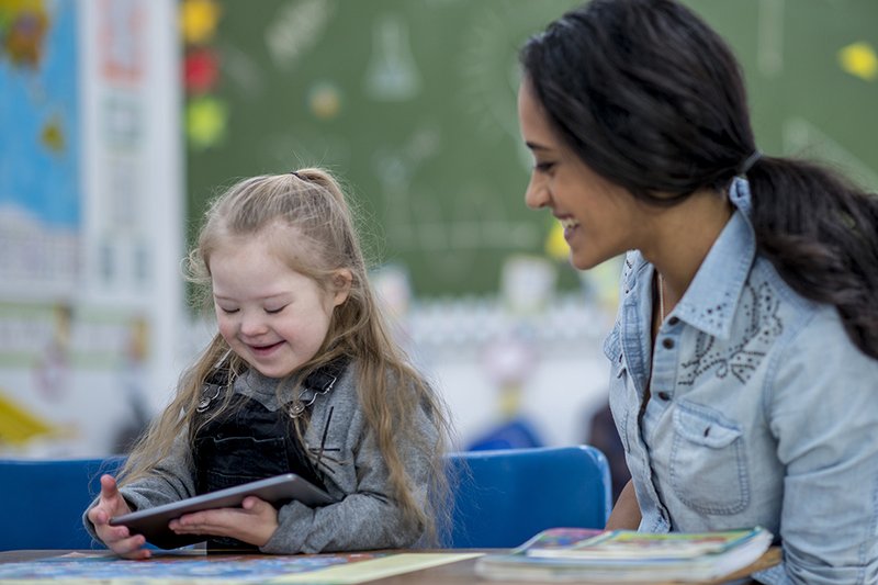 Down syndrome girl using tablet with woman.jpg