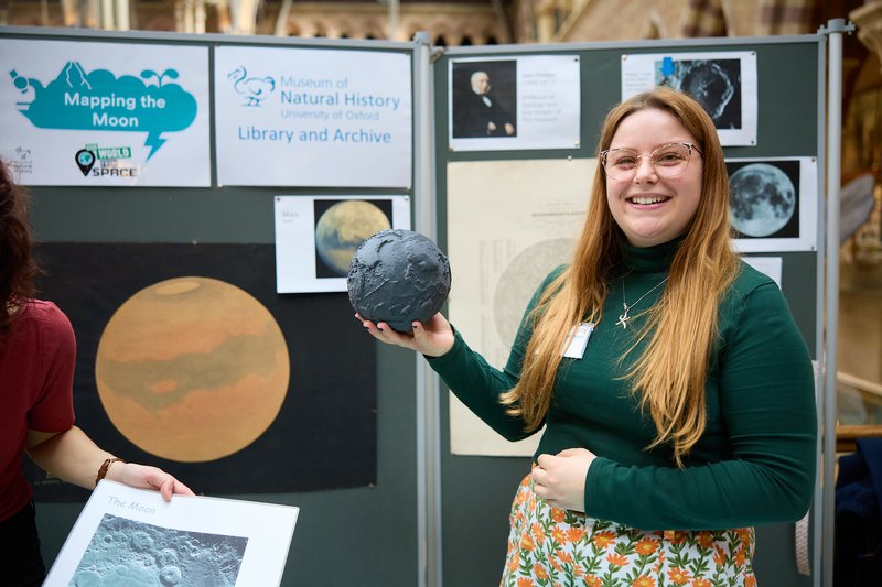 Photo of woman holding a model of the moon at Super_Science_Saturday