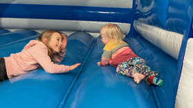 Girl and toddler with Down syndrome on bouncy castle